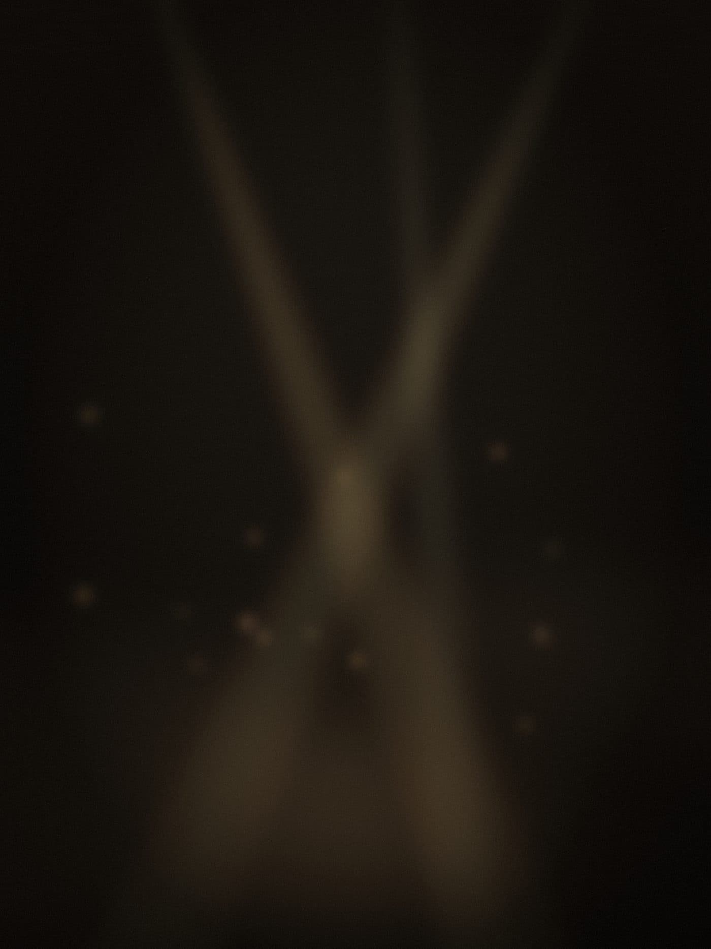 crossing brass light beams over a warm dance-floor glow in a dark room